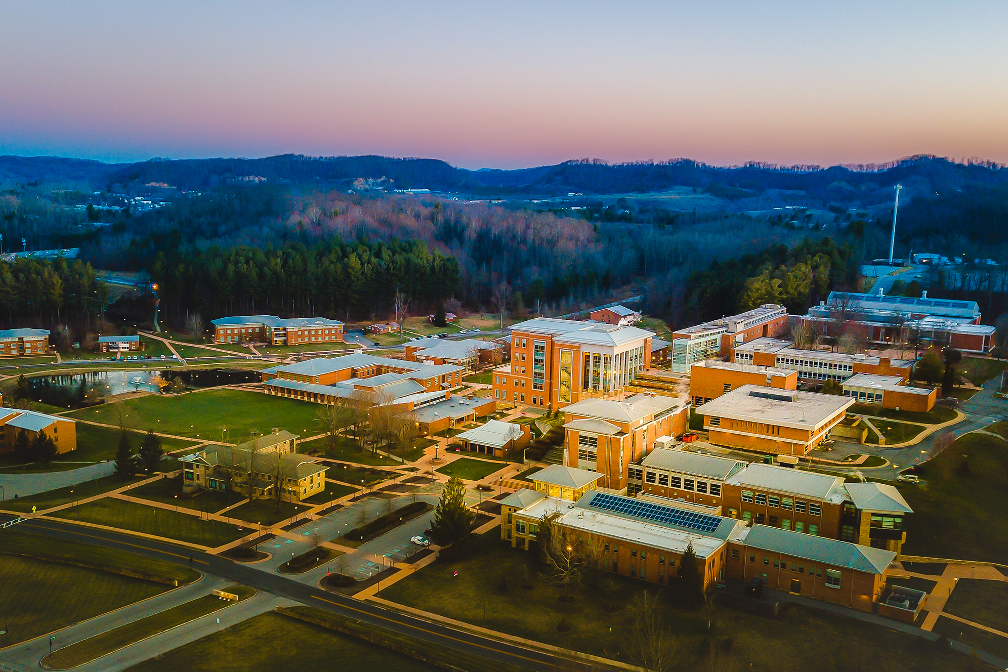 A sunset aerial of several college buildings with mountains in the background