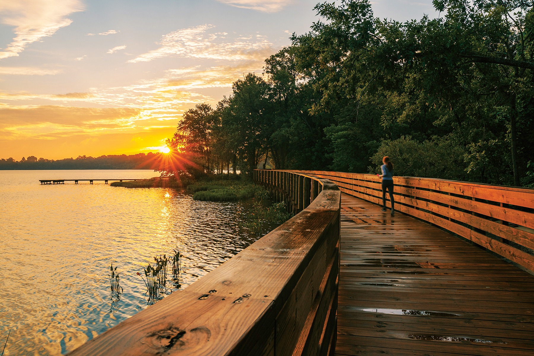 A woman running along a wooden platform next to a river
