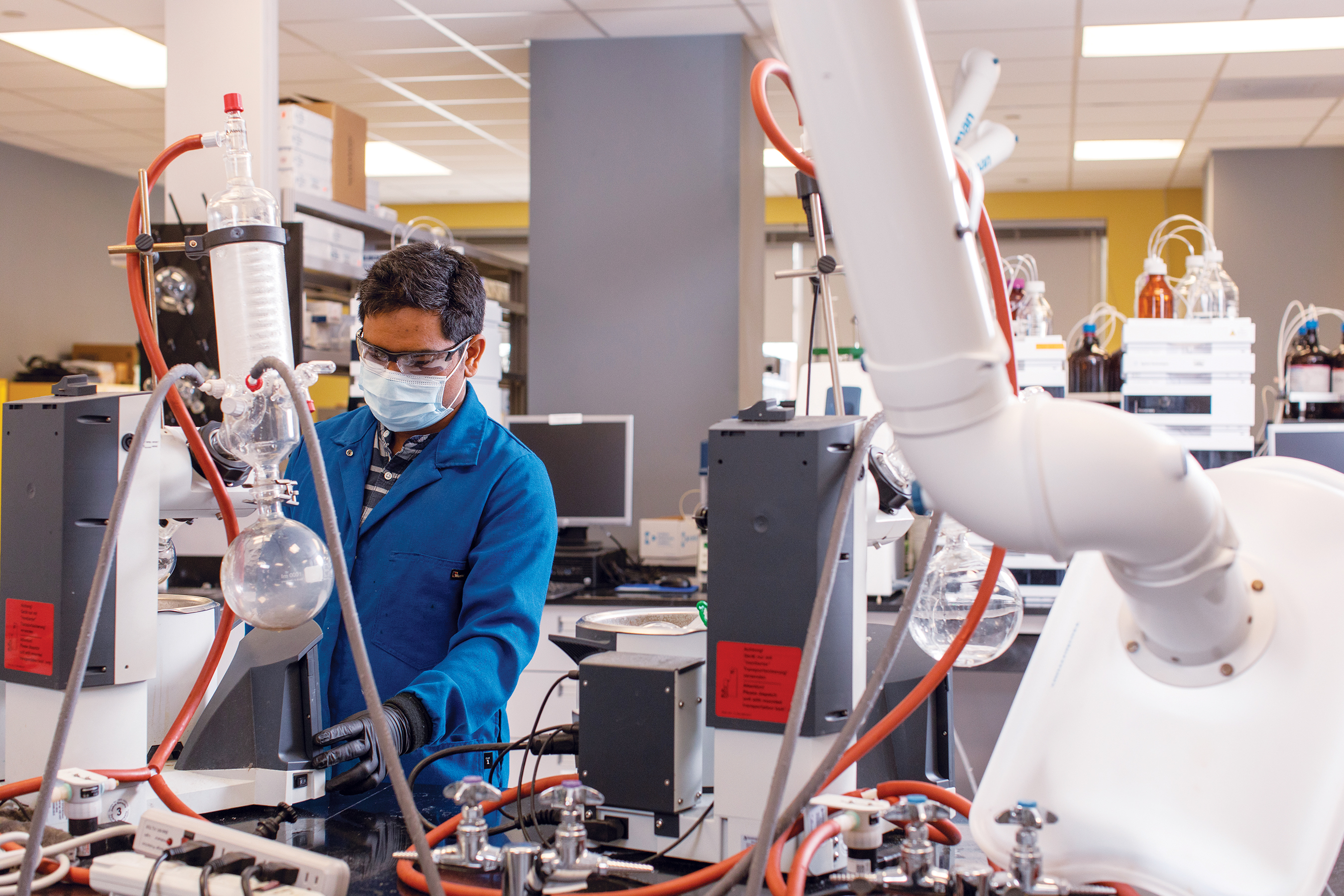 A man in a blue lab coat working in a laboratory