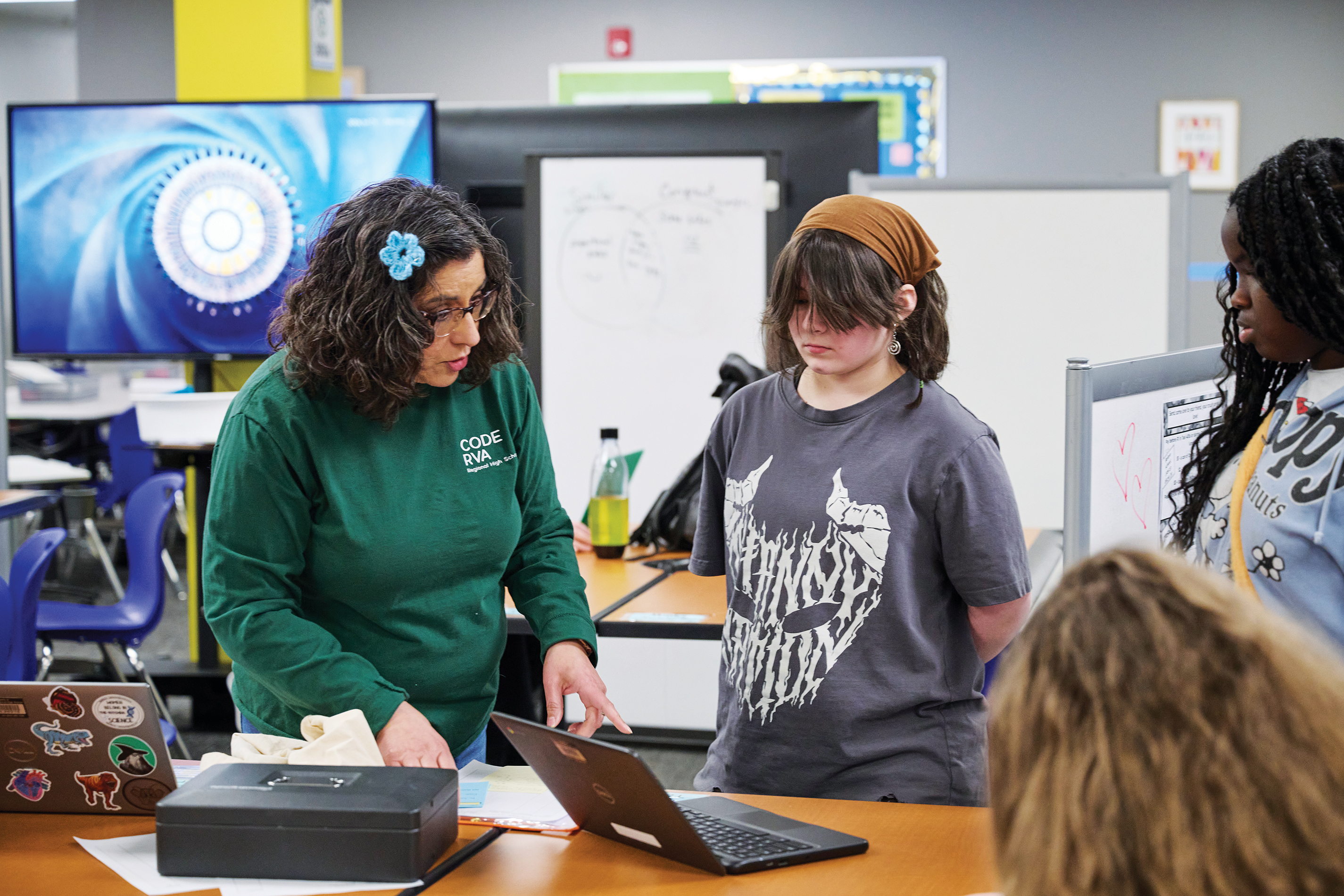 A CodeRVA Teacher and 3 students sitting around a laptop