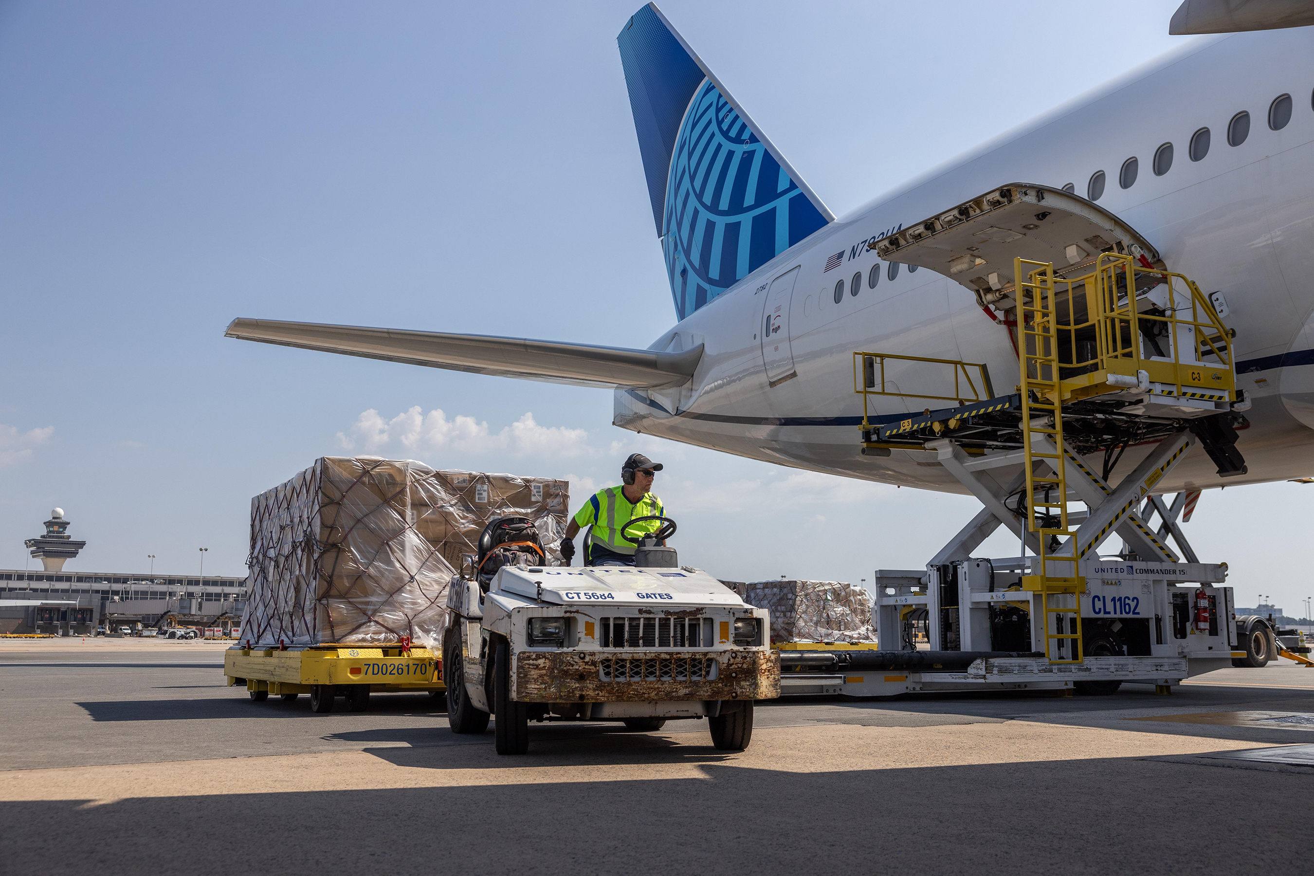 Airline worker transporting cargo at Washington Dulles International Airport.