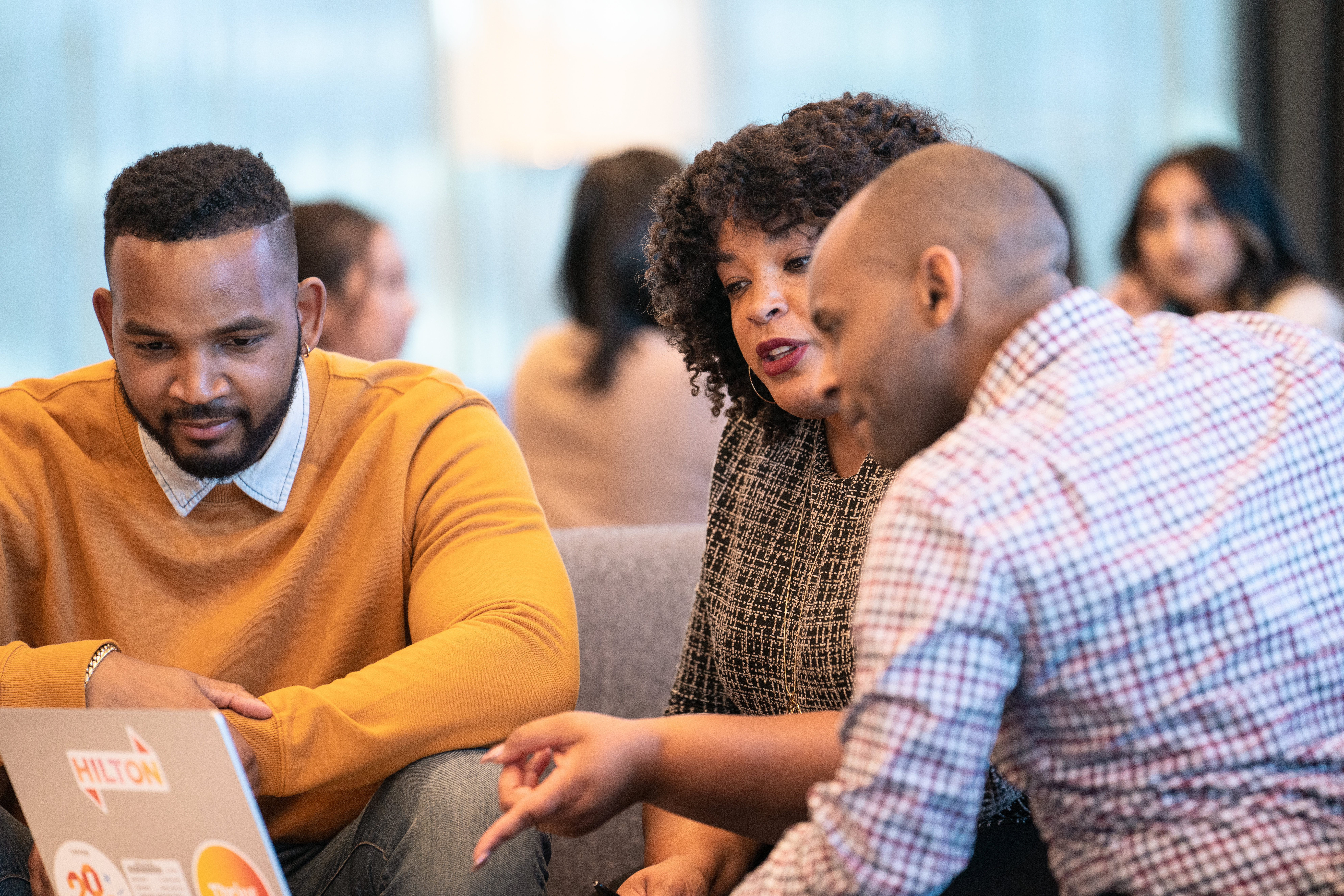 Three people sitting in front of a laptop at Hilton HQ. 