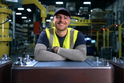 A smiling man leaning on a piece of equipment