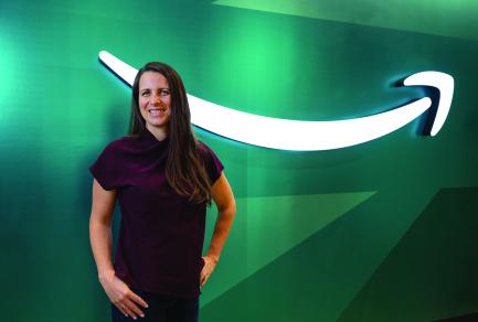 A woman standing in front of a green wall with the Amazon logo