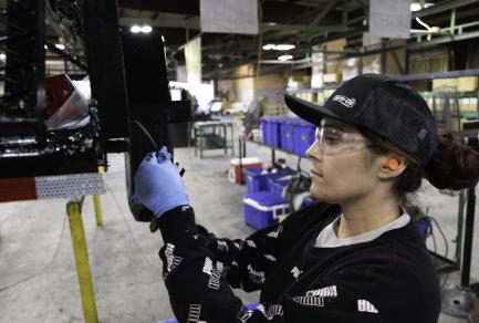 A woman working in a factory attaching a part to a trailer