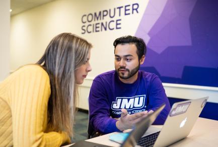 A man and a woman looking at a computer
