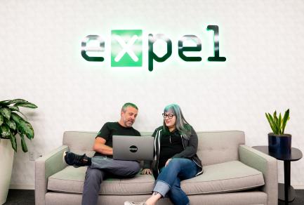 A man and a woman sitting on a couch and looking at a computer