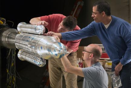 Three men working on a rocket booster