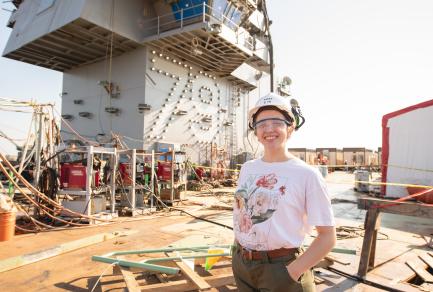 A woman in a hard hat standing on a ship
