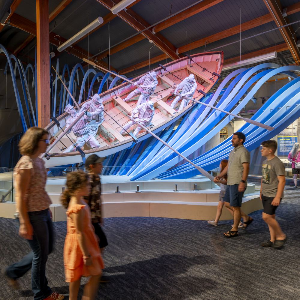 Museum guests pass a row boat display