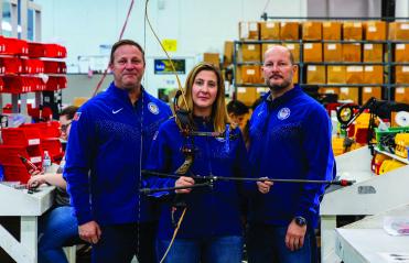 Three T.R.U. ball employees holding a bow and arrow 