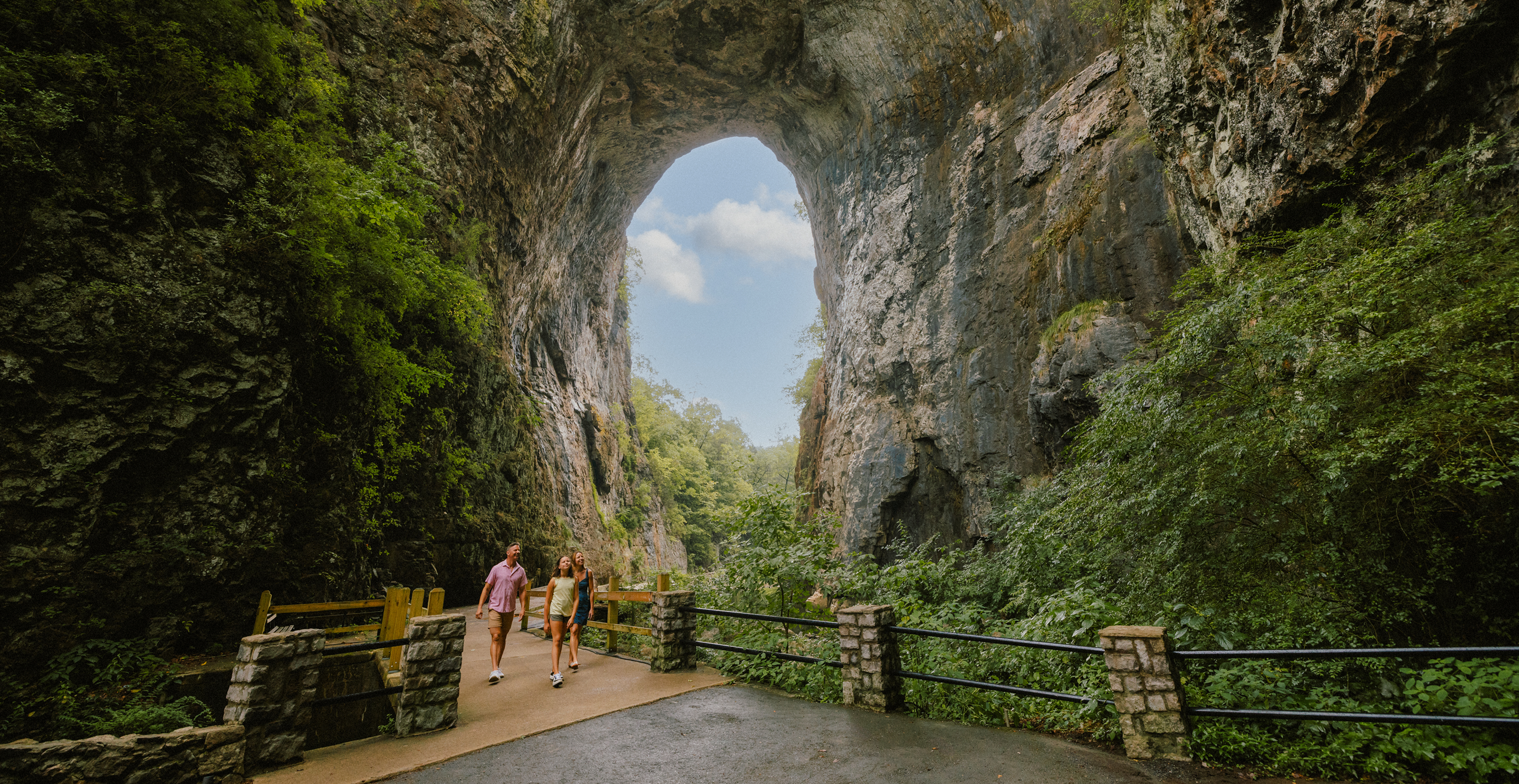 People walking beneath a massive natural rock arch.