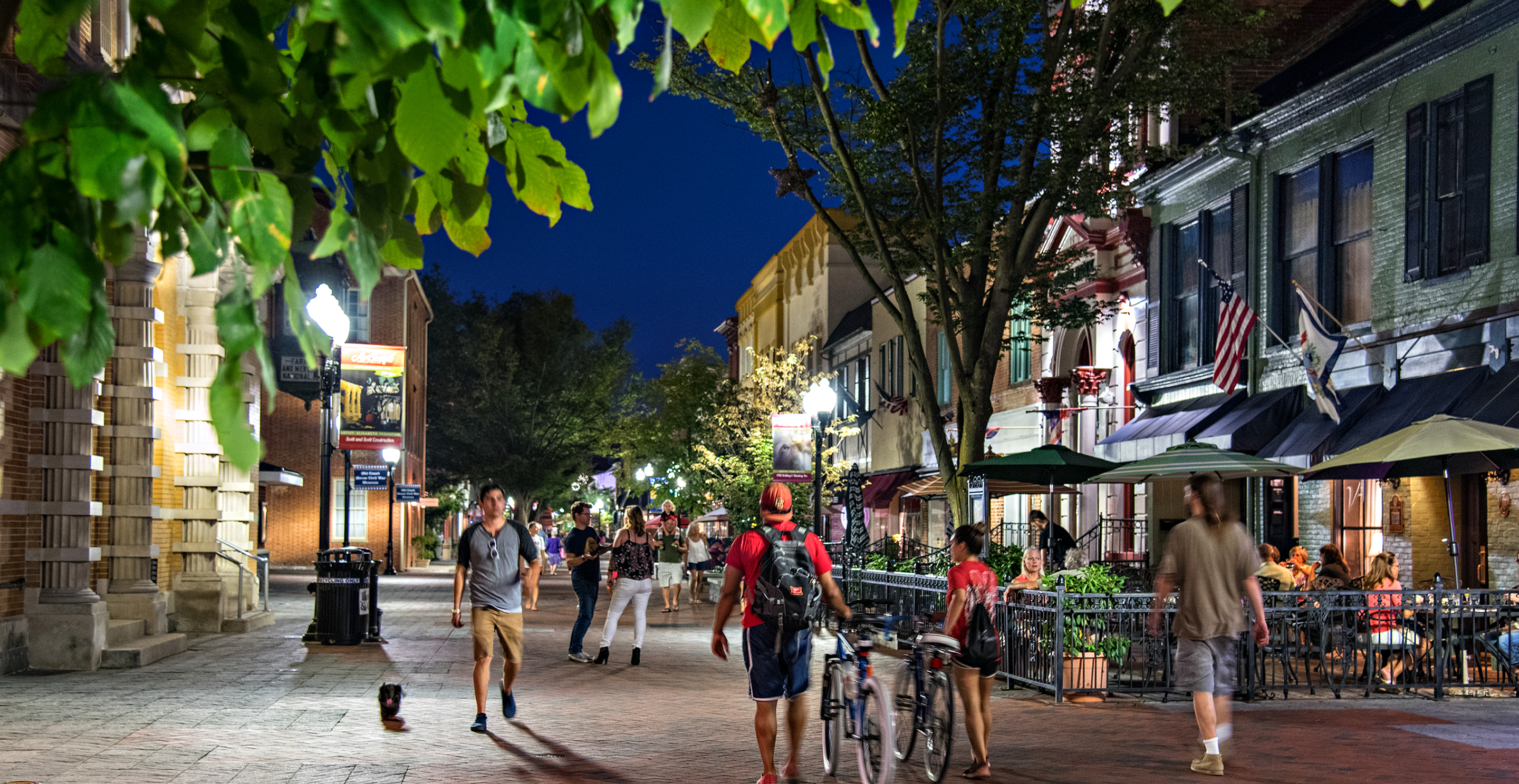 People walking and dining along a downtown pedestrian street at night