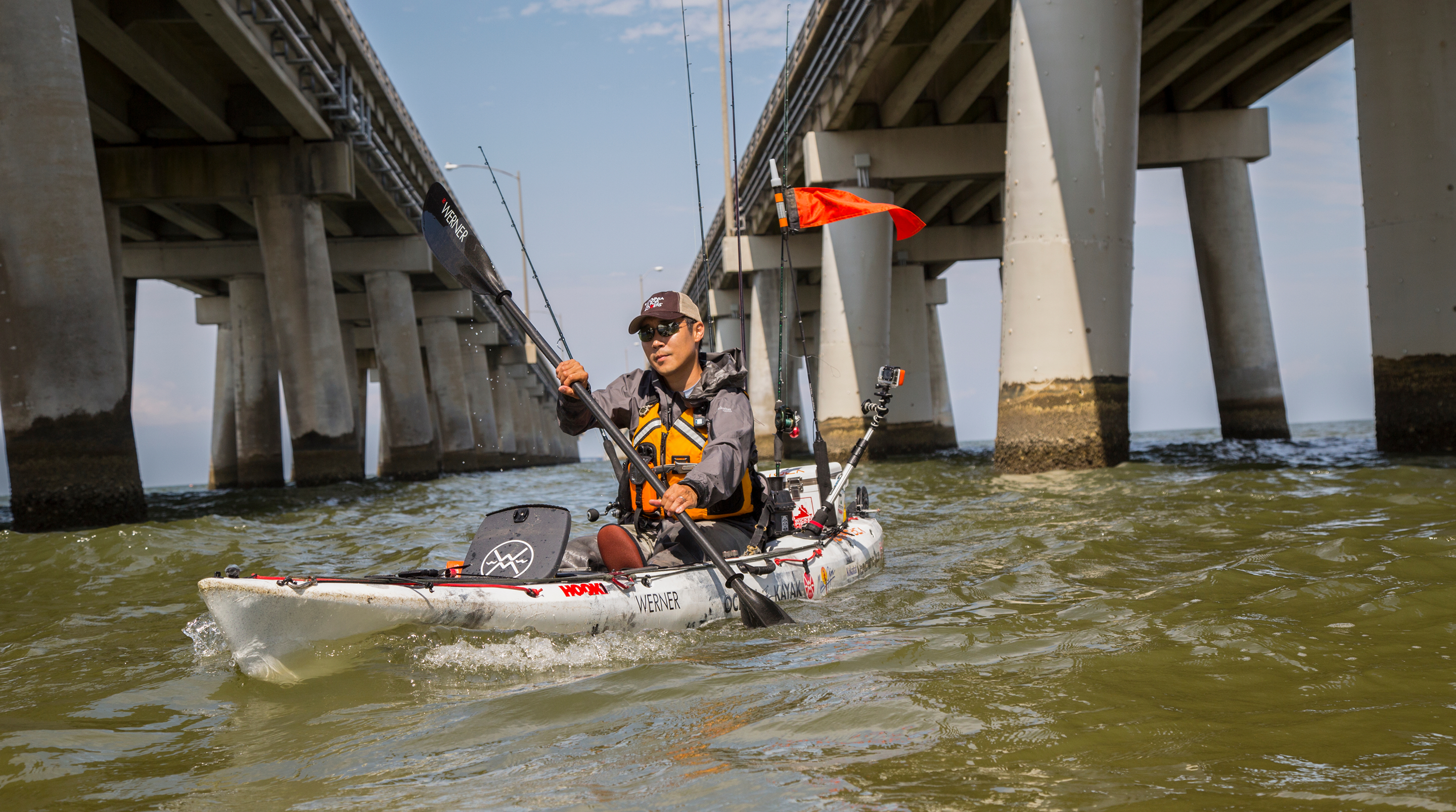Man kayaking beneath two bridges