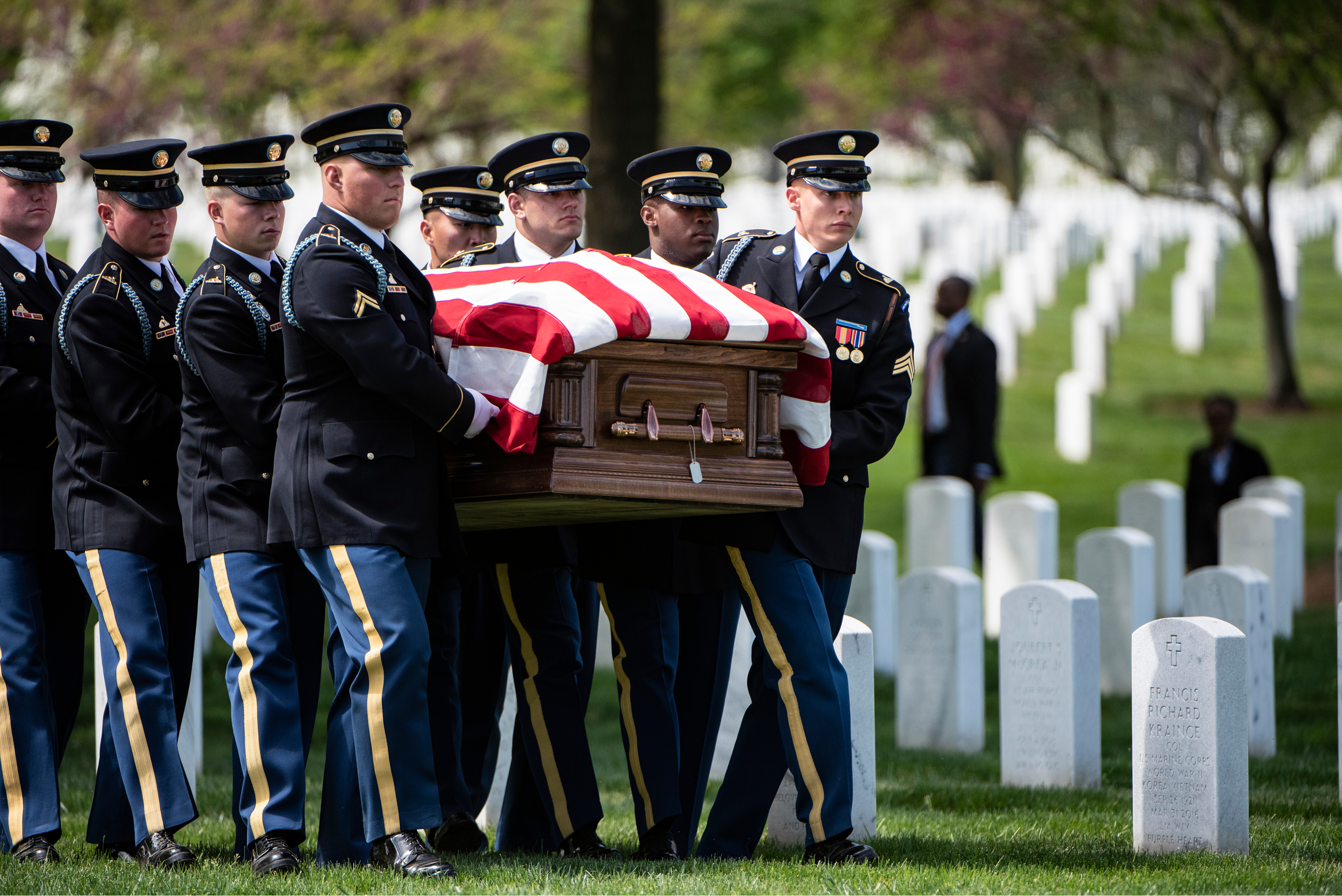 Uniformed servicemen carrying a coffin draped with an American flag