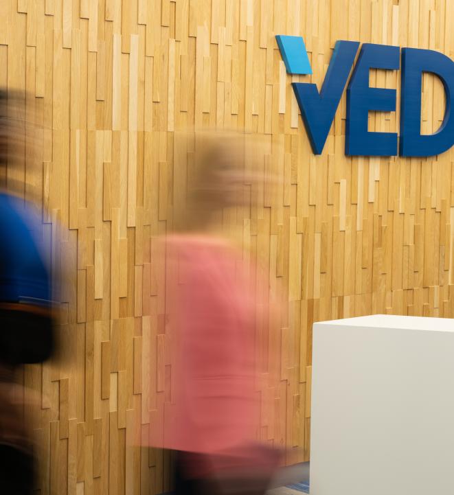 Blurred people walking in front of VEDP sign