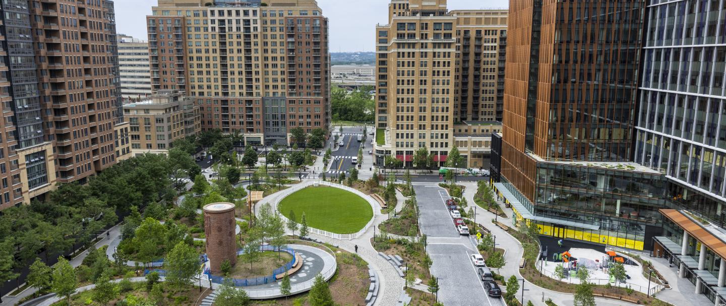 Several tall buildings surrounding a green space with paths