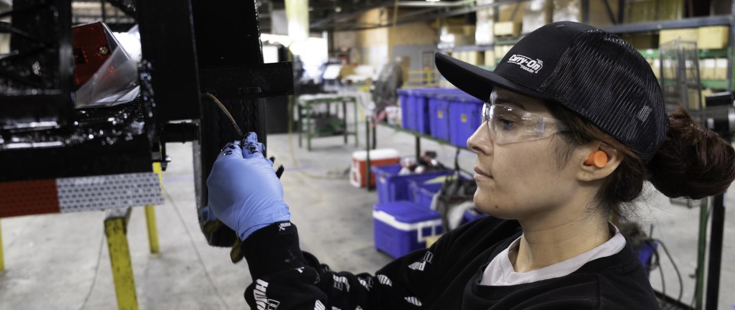 A woman working in a factory attaching a part to a trailer