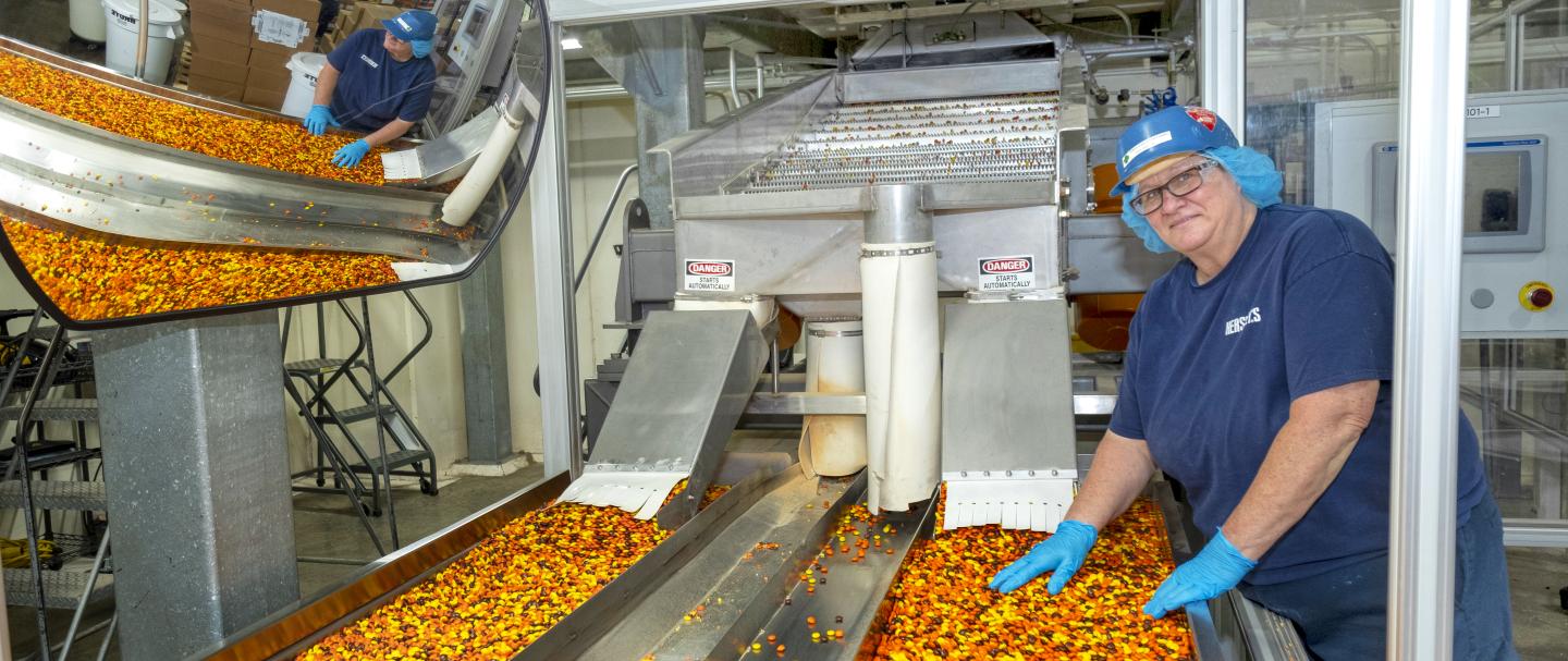 A woman working a sorting machine for Reese's Pieces