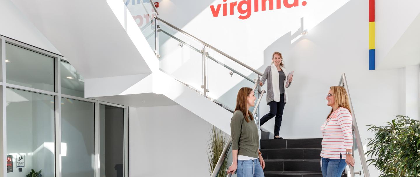 Three women standing on a staircase, smiling and talking