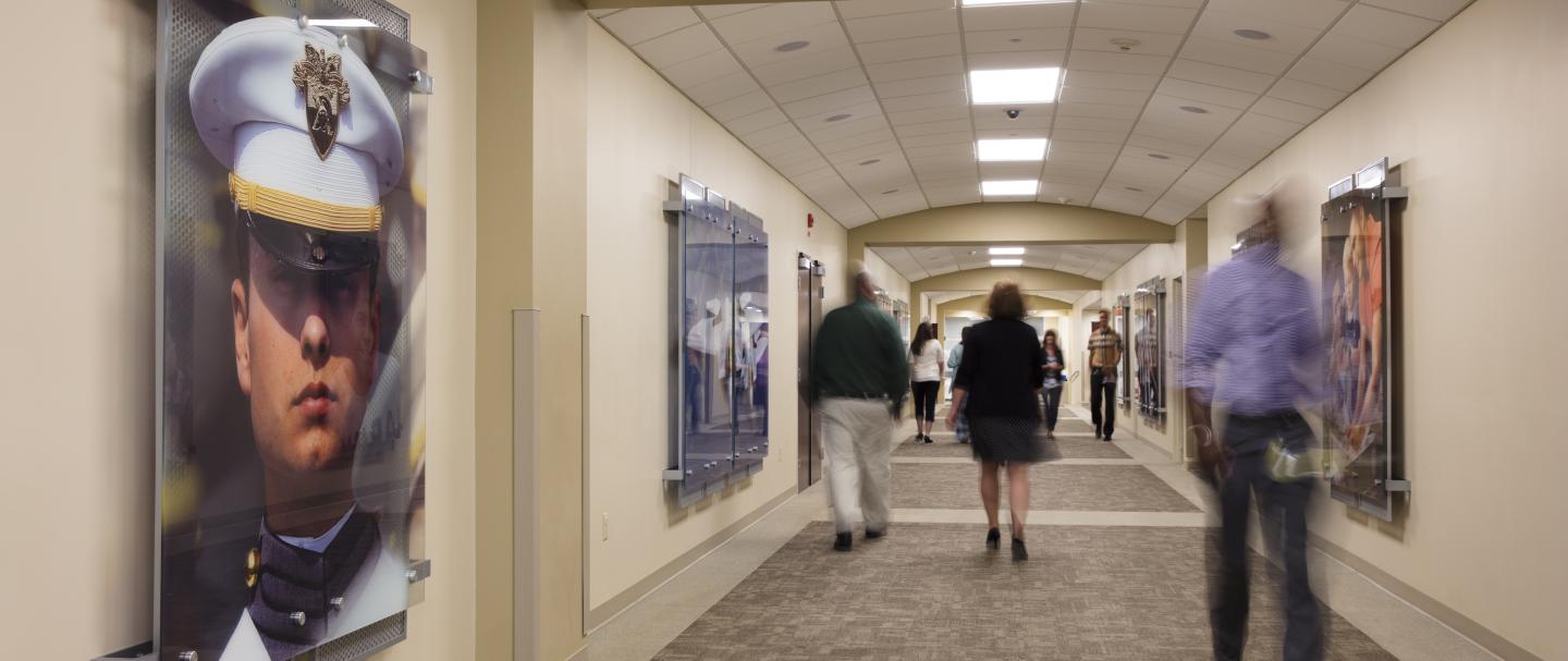 Several people walking down a hallway in both directions with art on the walls