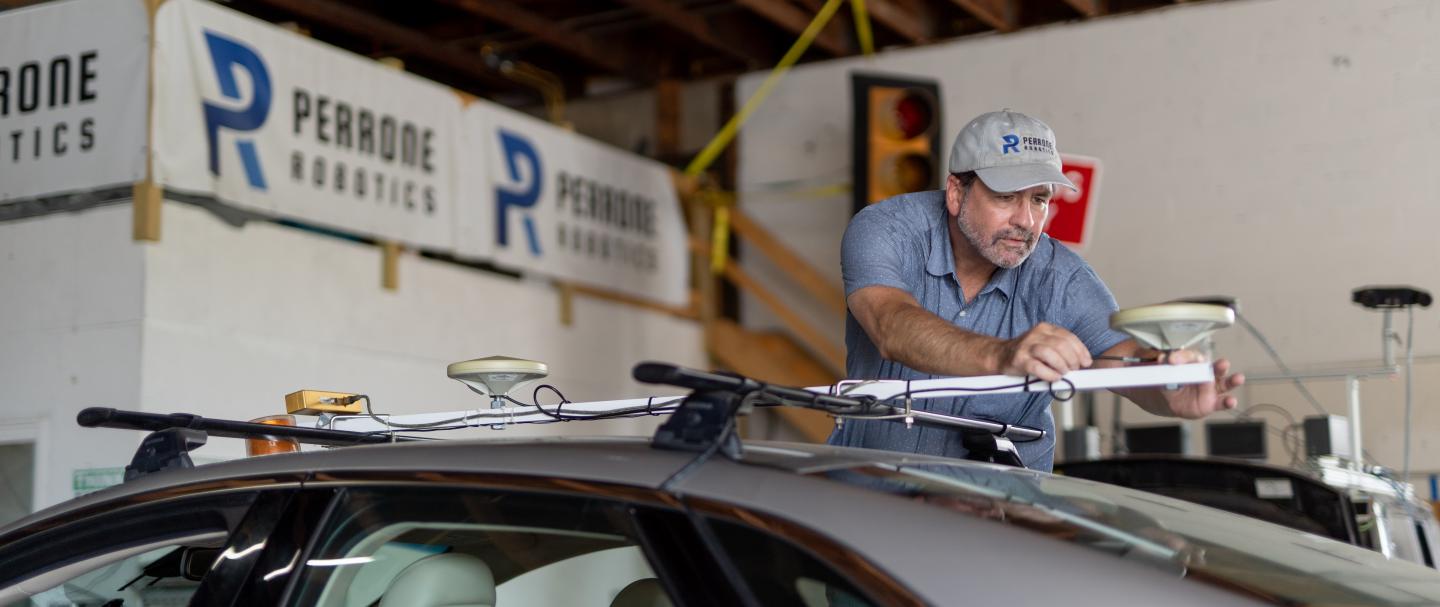 A man attaching a sensor to the top of a car