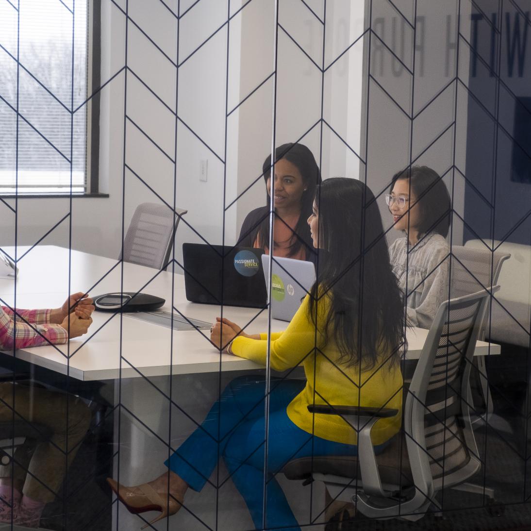 A man and three women talking around a table
