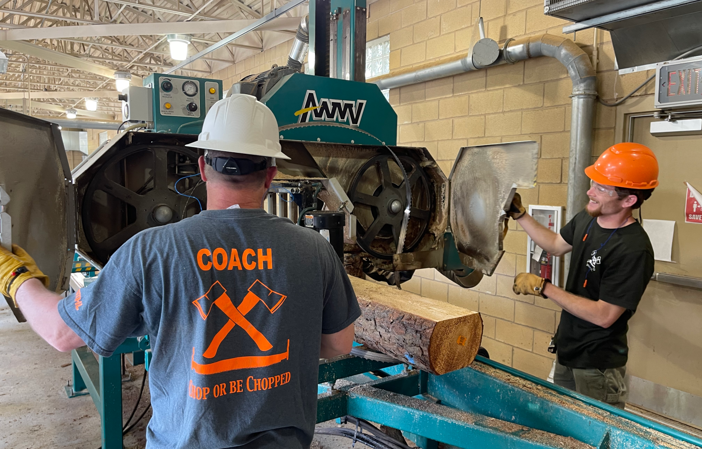Two men feeding a log into a machine