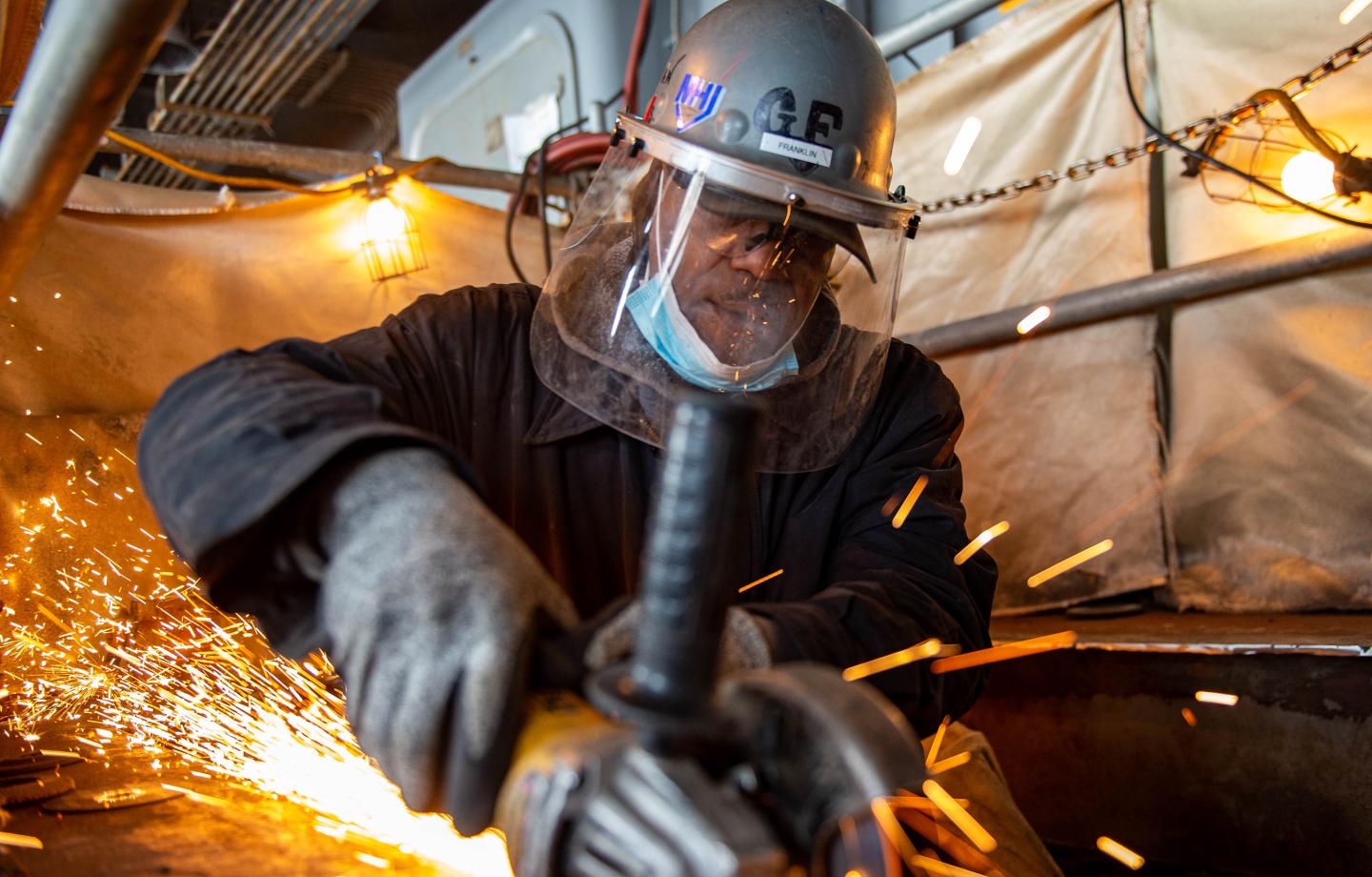 A man works welds together parts of a ship