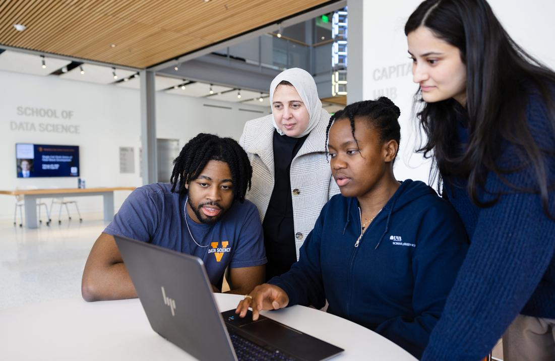 Photo of students sitting around a laptop