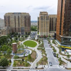 Several tall buildings surrounding a green space with paths