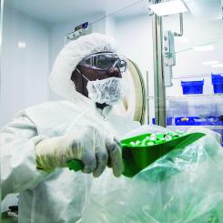 A man in protective gear scooping items into a container