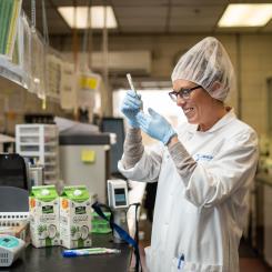 A woman in protective gear looks at a piece of equipment
