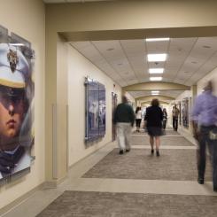 Several people walking down a hallway in both directions with art on the walls