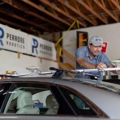 A man attaching a sensor to the top of a car