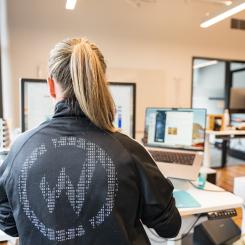 A woman typing on a computer with her back to the camera