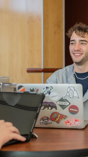 A young man smiling while working on a computer
