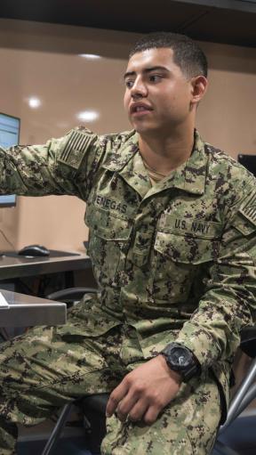 A man in military camo pointing at a computer screen