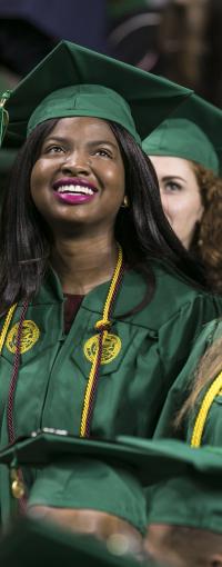 Three women in green graduation caps and gowns