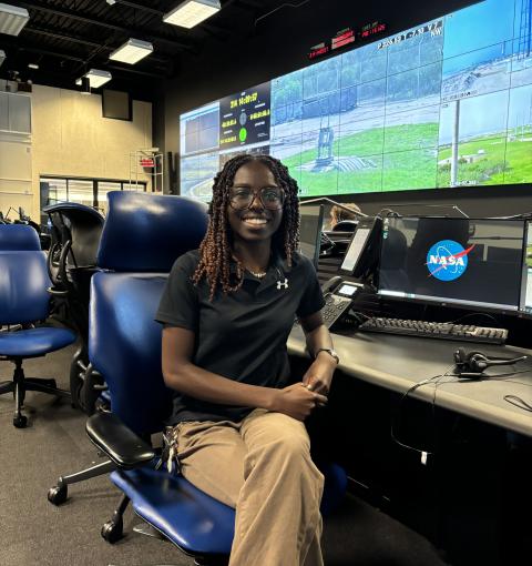 A young woman sitting at a desk in a NASA control room