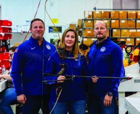Three T.R.U. ball employees holding a bow and arrow